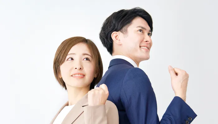 ガッツポーズをしているスーツ姿の男女